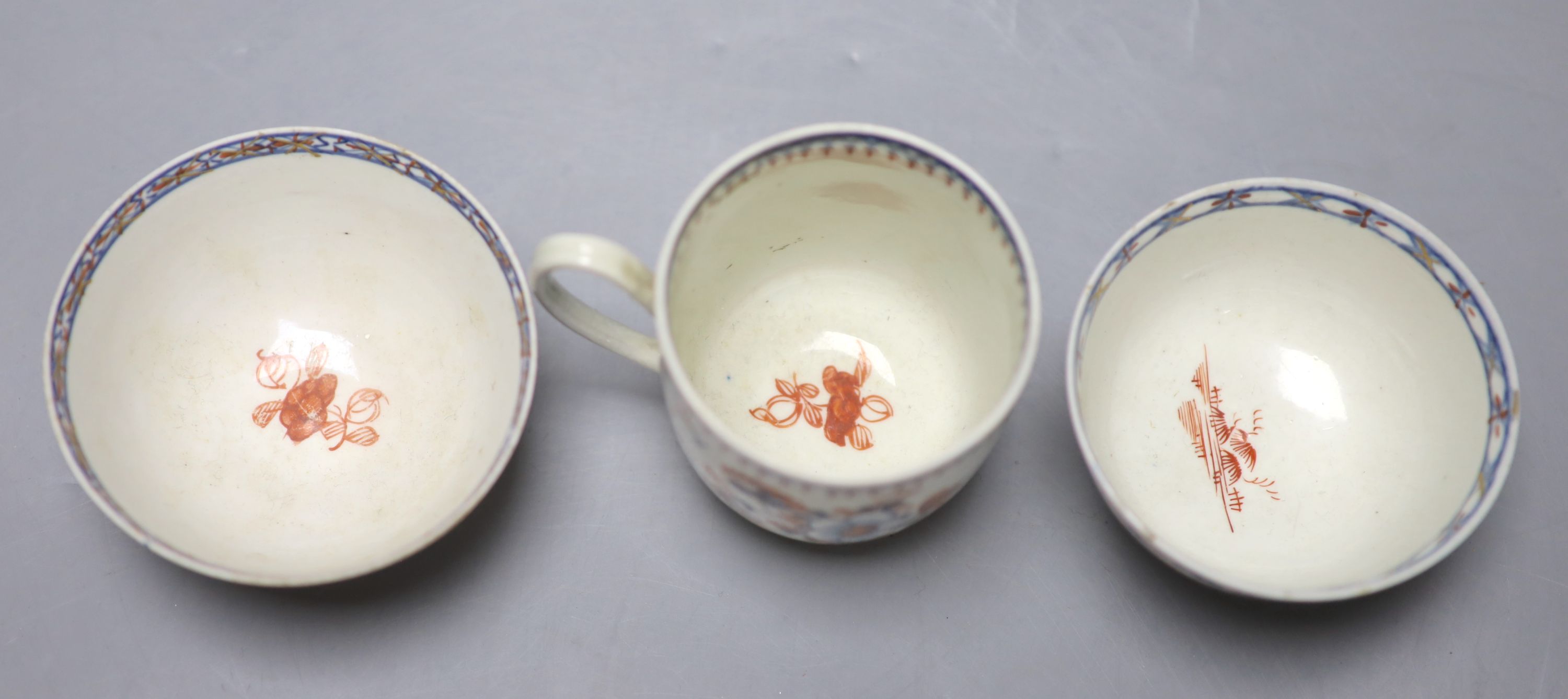 An 18th century Liverpool coffee cup and two teabowls, painted in blue with overglaze red highlights